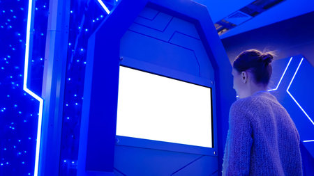 White screen, mockup, science, copyspace, template, isolated, technology concept. Woman looking at blank white display of interactive kiosk at exhibition or museum with futuristic sci-fi interiorの写真素材