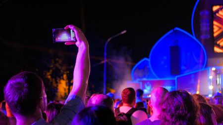 Unrecognizable man hands silhouette taking photo or recording video of live music concert with smartphone at night. Photography, entertainment and technology conceptの写真素材