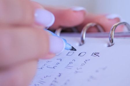 Woman hand putting mark on check boxes of to do list in personal vintage notebook organizer - close...