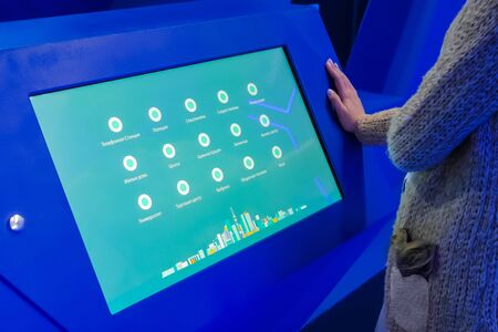 MOSCOW, RUSSIA - JUNE 05, 2019: Smart Expo. Woman looking at interactive display kiosk with multimedia presentation about russian smart city system in Moscow at exhibition with futuristic interiorのeditorial素材