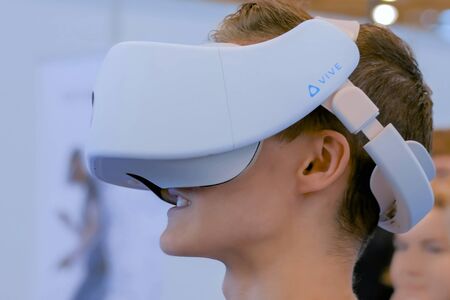 MOSCOW, RUSSIA - March 1, 2019: Virtual Reality Exhibition. Man using Vive virtual reality headset and looking around at technology exhibition. VR, augmented reality and entertainment conceptのeditorial素材