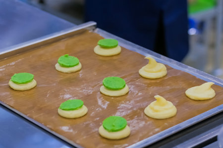 Process of preparing shortbread cookies with bright green filling on kitchen table at cuisine of...