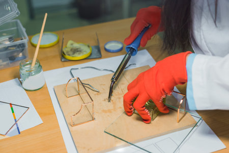 Professional woman decorator, designer working with soldering iron and making glass gift keepsake...