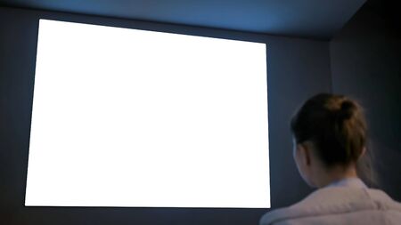 White screen, technology, isolated, futuristic, template, mock up, entertainment concept. Woman looking at large wall blank interactive white display at science exhibition, museum or cinemaの写真素材
