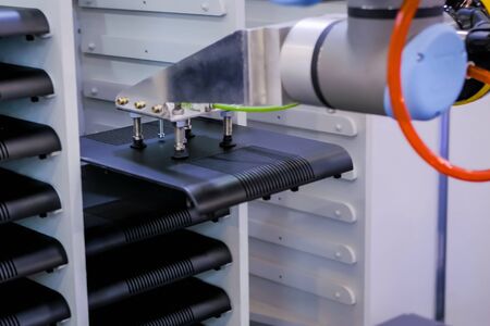 Pick and place robotic arm manipulator moves black parts of computer device at modern robot exhibition, trade show, plant, factory - close up view. Quality control and automated technology conceptの写真素材