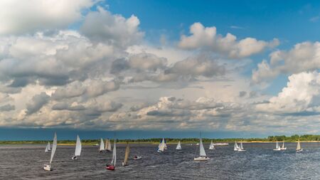 Sailing yachts at sport regatta competition race on river. White clouds against blue sky. Navigation, freedom, entertainment, outdoor sport activity conceptの写真素材