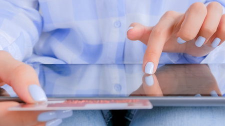 Woman using black digital tablet device and entering security code of red credit card. Online...