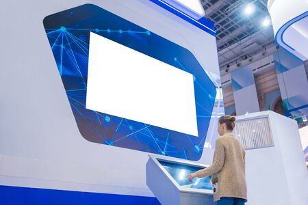 White screen, mock up, template, copyspace, isolated concept. Woman looking at blank large wide interactive wall white display at modern technology exhibition or museum with futuristic sci-fi interiorの写真素材