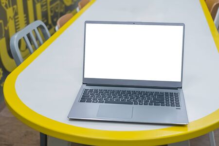 Mockup image of grey laptop with white blank screen on wooden table at cafe, restaurant. Mock up, copyspace, interior, freelance workspace, template, entertainment and technology conceptの写真素材