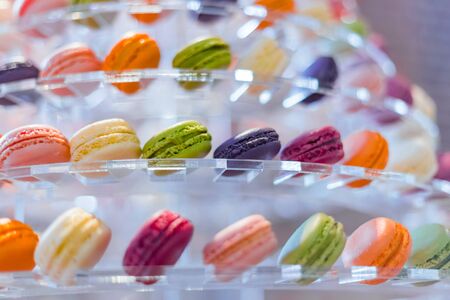 Assortment of bright colorful macarons or macaroons cakes for sale on shelf of candy shop, market, cafe or bakery. Dessert, biscuit, sweet food and traditional french cuisine conceptの写真素材