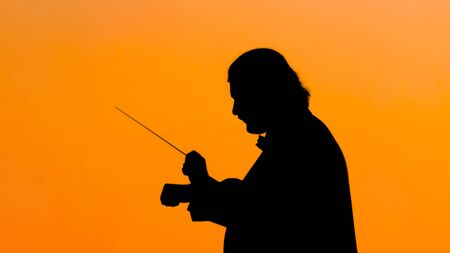 Symphony classical concert - portrait of unrecognizable man conductor silhouette at sunset. Music and culture conceptの写真素材