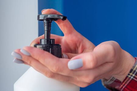 Woman pushing dispenser, squeezing out antiseptic gel on palm, cleaning hands - close up side view. Disinfection, protection, prevention, COVID-19, coronavirus, safety, sanitation conceptの写真素材