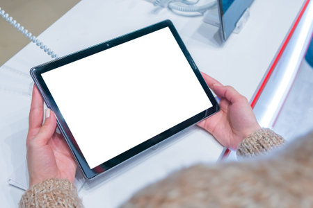 Mockup image: woman customer testing new model of tablet with blank white display at electronic...