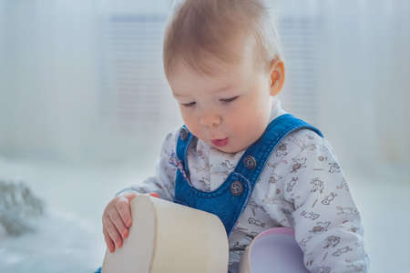 Little boy playing with empty gift box in bright white room at home - close up view. Christmas, New Year, family, childhood, leisure time, holiday conceptの写真素材