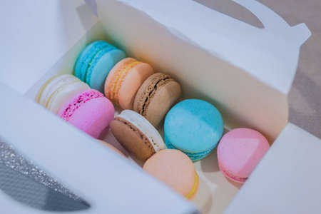 Colorful macaroons in white gift box on table at candy shop, market, cafe or bakery - close up view. Dessert, biscuit, sweet food and traditional french cuisine conceptの写真素材