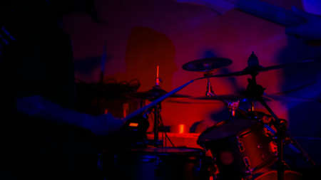 Unrecognizable male drummer silhouette playing drums. Red and blue light, low key. Entertainment and art conceptの写真素材