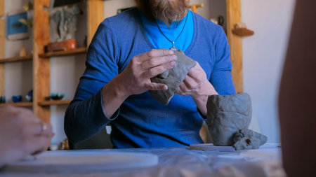 Pottery class and workshop: professional male potter showing how to make clay mug in pottery studio....