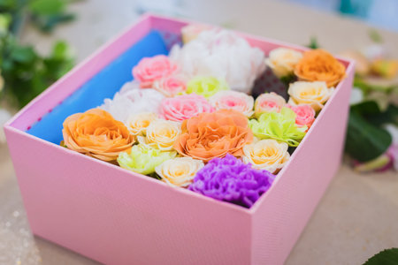 Close up view of gift box with colorful flowers - rose, peony, carnation on table at flower shop....