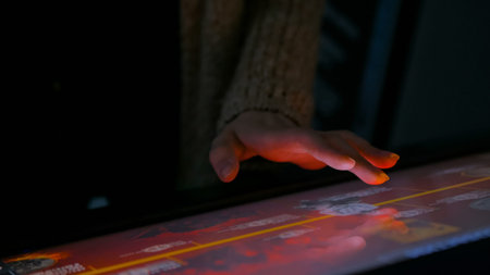 Woman using interactive touchscreen display in modern historical museum. Evening time, lowlight....