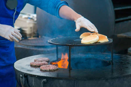 Chef preparing burgers at street food festival. Outdoor cooking, gastronomy and street food conceptの写真素材