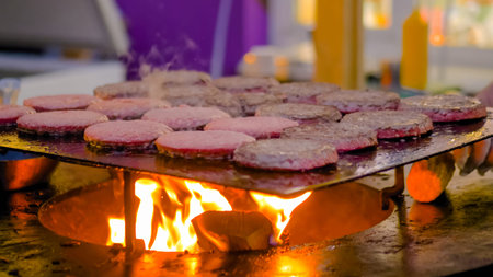 Process of grilling fresh meat cutlets for burgers on brazier with hot flame at summer local food...