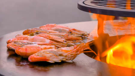 Process of grilling fresh red king prawns on round black brazier at summer local food market - close up view. Outdoor cooking, barbecue, gastronomy, seafood, cookery, street food conceptの写真素材