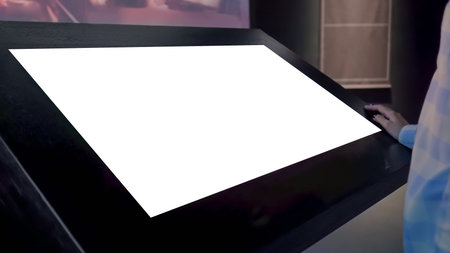 Woman looking at horizontal blank digital interactive white display kiosk at exhibition or museum...