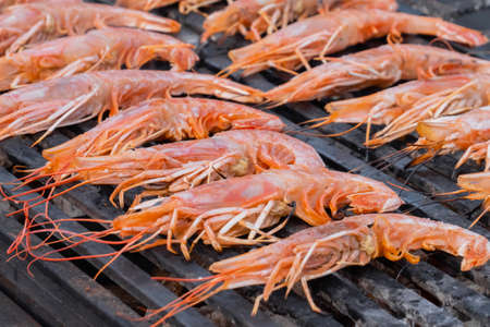 Process of cooking fresh red langoustine shrimps, prawns on grill at summer local food market - close up. Outdoor cooking, barbecue, gastronomy, seafood, cookery, street food conceptの写真素材