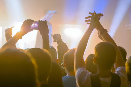 People hands silhouette taking photo or recording video of live music concert with smartphone. Crowd...