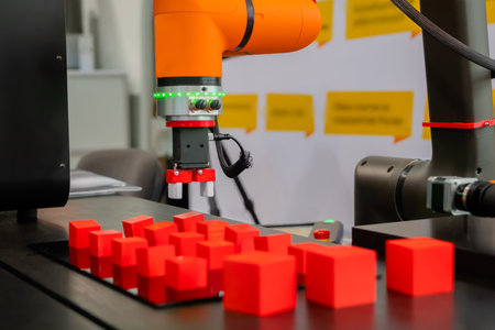 Pick and place robotic clamp arm manipulator moving red toy blocks at modern robot trade show,...