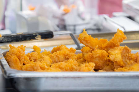 Crispy deep fried fish or chicken meat in restaurant food container at summer outdoor food market: close up. Seafood, takeaway, gastronomy, cookery, street food conceptの写真素材