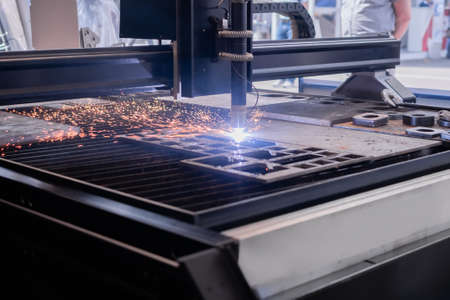 Automatic cnc plasma cutting machine working with sheet metal with many bright sparks at factory, plant. Metalworking, industrial, equipment, technology, machining, manufacturing conceptの写真素材