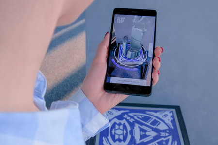 MOSCOW, RUSSIA - JANUARY 5, 2020. Woman using smartphone with augmented reality app and rotating 3d...