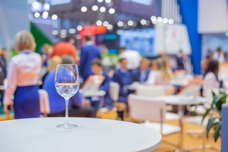 Close up view: glass of water, champagne or wine on white table against blurred business meeting, conference, seminar background. Corporate and communication conceptの写真素材