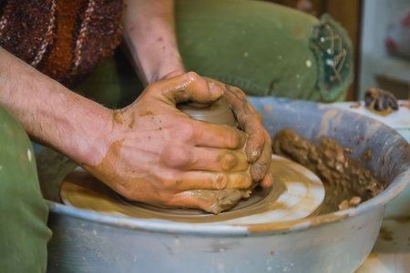 Close up view - professional male potter making pot on pottery wheel at workshop, studio. Handmade, art and handicraft conceptの写真素材