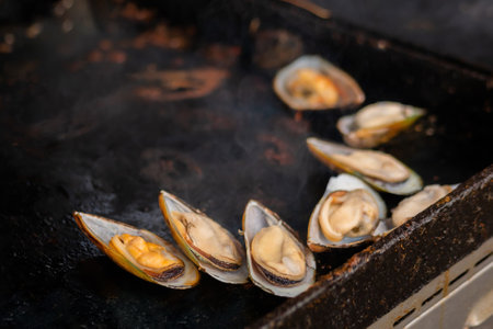 Process of cooking mussels, clams on grill at summer local food market - close up. Outdoor cooking, barbecue, gastronomy, seafood, cookery, street food conceptの写真素材