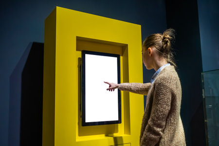 Woman hand using vertical white blank interactive touchscreen display of electronic multimedia kiosk in dark room - scrolling and touching. Mock up, copyspace, template and technology conceptの写真素材