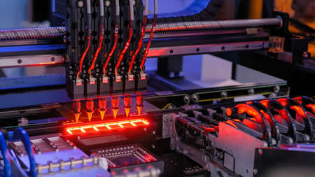 Automatic SMD pick and place machine during work - assembly of computer circuit board at factory. Automated technology, industrial, robotic, electronic, production, manufacturing conceptの写真素材