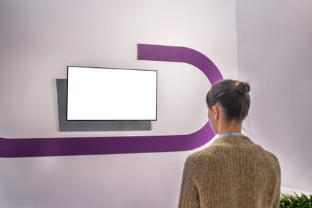 Woman looking at blank digital interactive white display wall at exhibition or museum with...