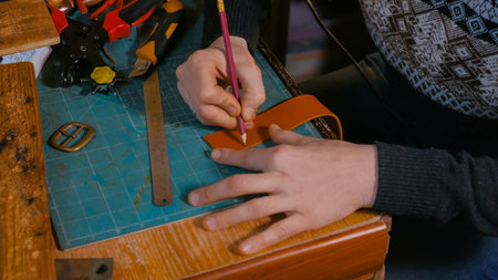 Professional male skinner, tanner working with genuine leather belt at workshop, studio. Handmade...