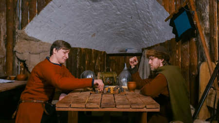 Two men in russian ethnic suit playing medieval popular strategy board game - tafl. Folk, competition and traditional conceptの写真素材
