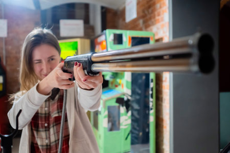 Woman gamer playing vintage shooting arcade game - selective focus. Gaming, 80s, hobby, old school,...