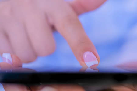 Close up top view - woman hands using black smartphone with interactive touchscreen display in white room or office - scrolling and touching. Relax, entertainment and technology conceptの写真素材