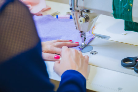 Professional tailor, fashion designer sitting and working at sewing studio, atelier. Close up view of woman hands using sewing machine. Fashion and tailoring conceptの写真素材