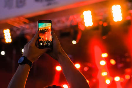 Man hands taking photo or recording video of live music concert with smartphone in front of stage of nightclub - close up. Photography, entertainment, technology conceptの写真素材