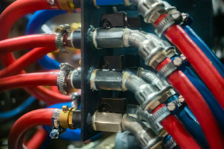 Hydraulic high pressure hoses and valves on mold control system of water cooling with red and blue tubes - part of automatic injection molding machine: close up viewの写真素材