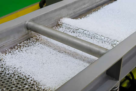 Recycled plastic granules - propylene or polyethylene pellets on shale shaker, conveyor belt of waste plastic recycling machine. Environmental protection, separation, automated technology conceptの写真素材