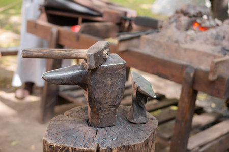 Hammer and blacksmith anvil at outdoor forge, workshop - close up, selective focus. Handmade,...