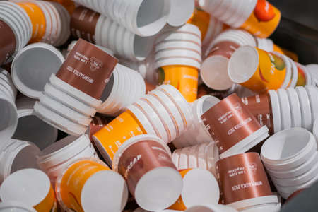 MOSCOW, RUSSIA - JUNE 10, 2020: Package Exhibition. Many stacks of empty orange and brown plastic cups at warehouse, factory, plant - close up. Manufacturing, recycling, industry, technology conceptのeditorial素材