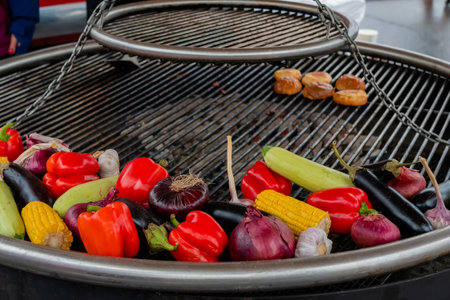 Process of grilling healthy vegetables - pepper, corn, zucchini, onion, garlic on brazier at summer outdoor food market. Vegetarian, cookery, gastronomy and street food conceptの写真素材